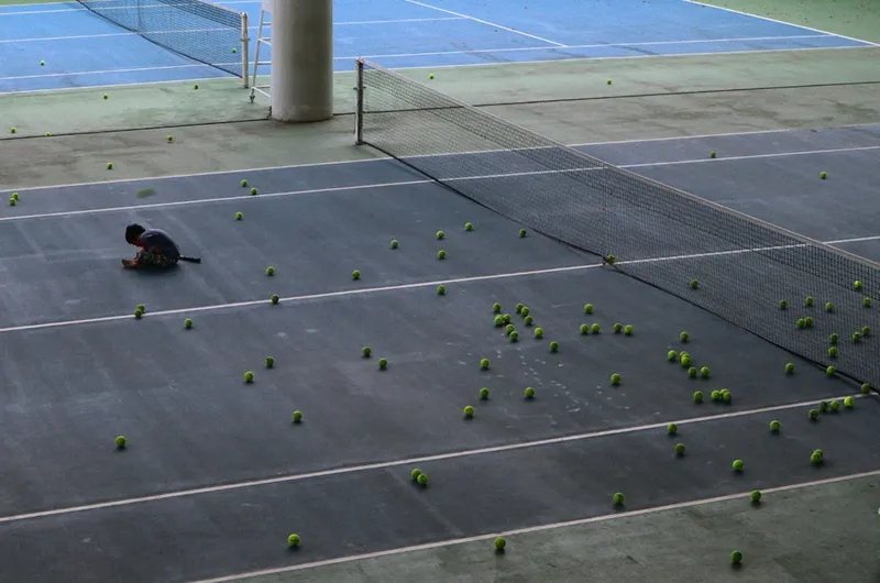 A tennis court filled with lots of tennis balls